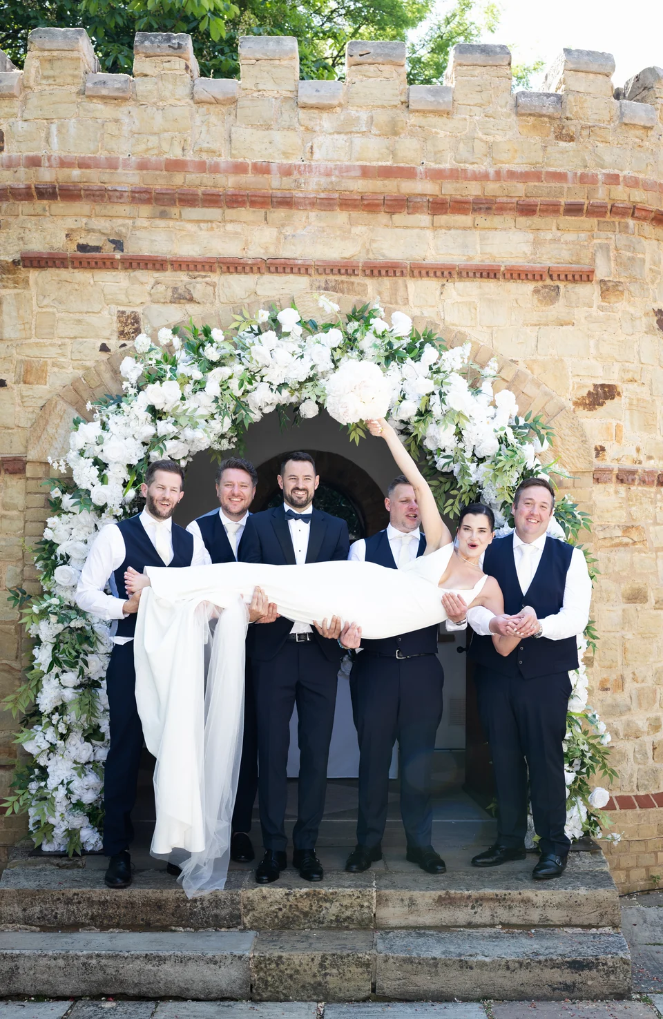 Wedding party gathered by an old brick archway