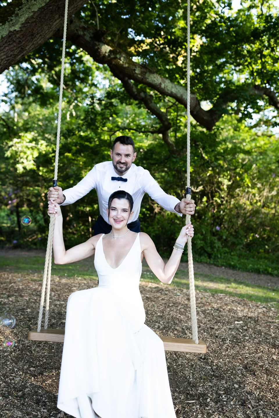 Bride on a garden swing with the groom behind her