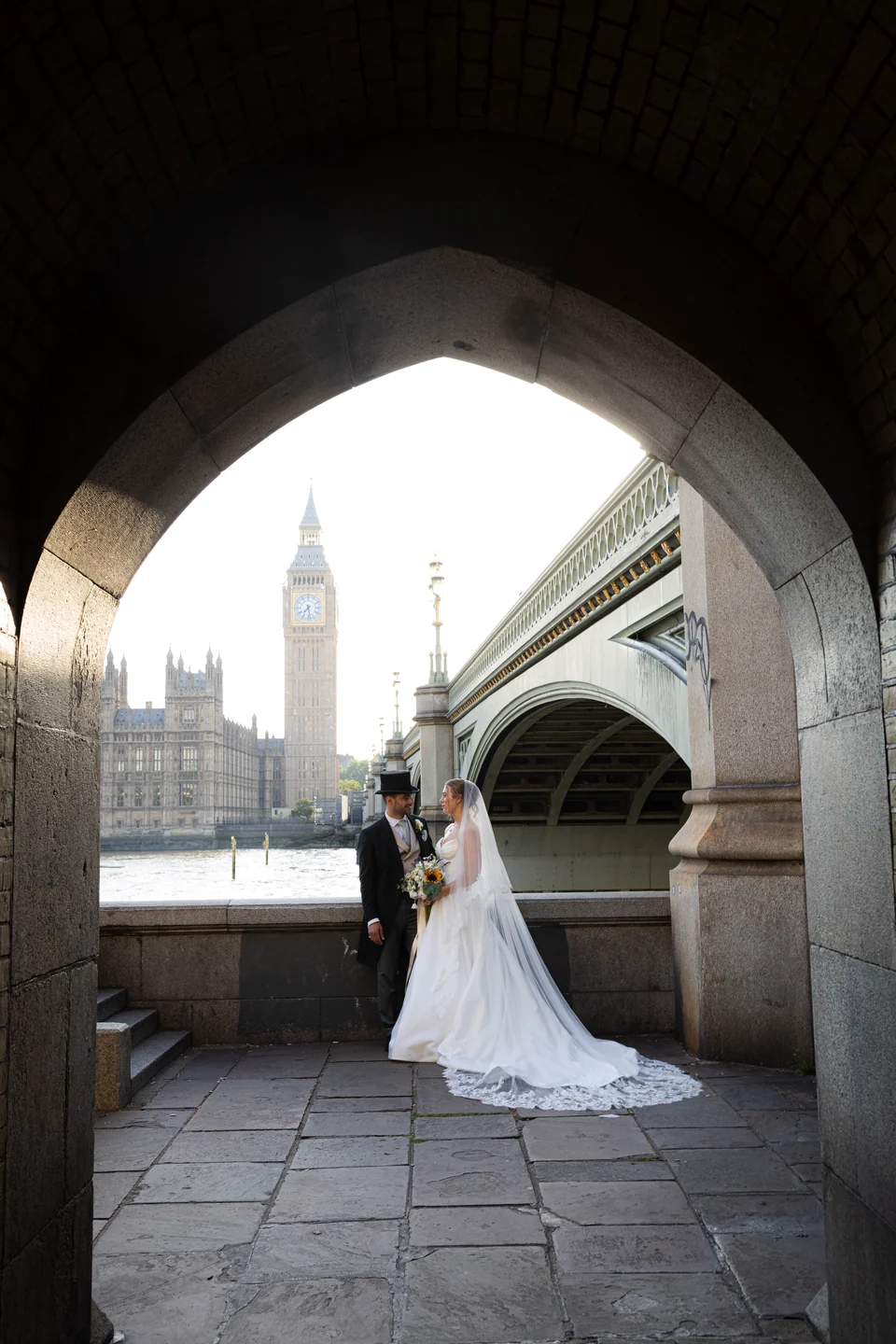 Wedding couple beneath an arch beside Westminster Bridge