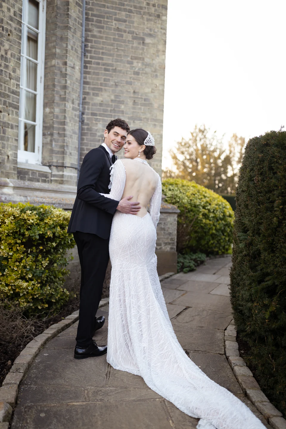 Newlyweds embracing outside a stone building