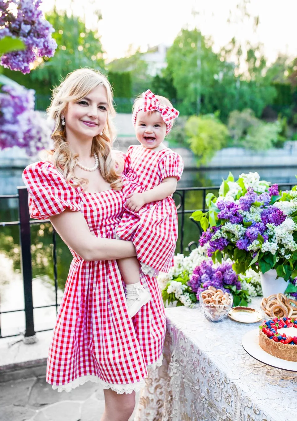 A cheerful outdoor tea party scene with matching gingham dresses and purple floral decorations.