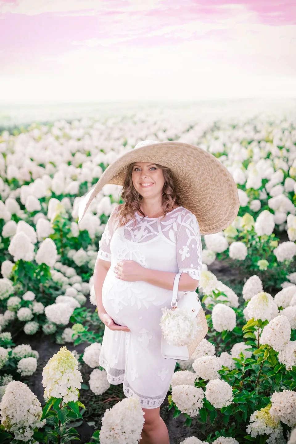 A serene scene in a hydrangea garden featuring a white lace dress and wide-brimmed sun hat among blooming flowers.