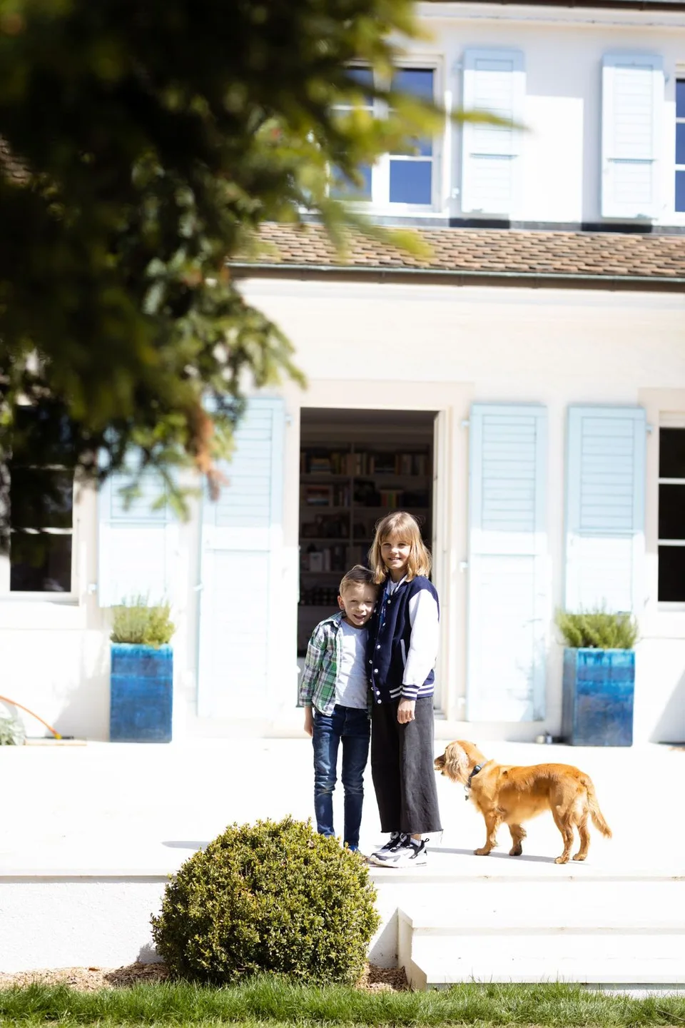House exterior view with blue shutters and golden dog in foreground.