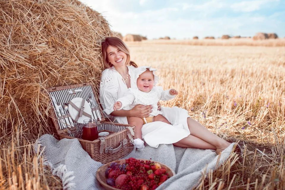 A picturesque picnic scene in a wheat field with a wicker basket and fresh strawberries at sunset.
