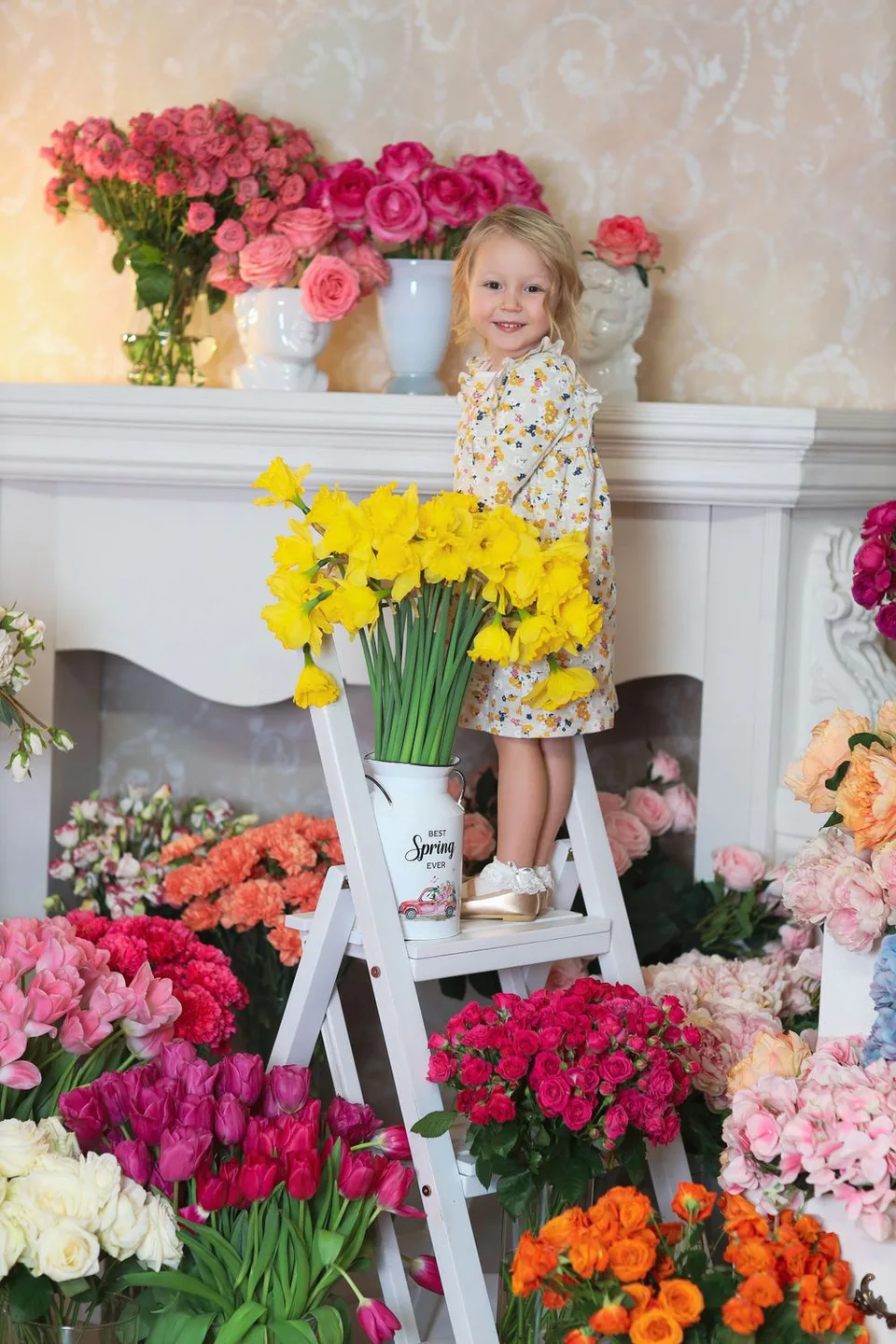 Colorful spring flower display with daffodils and roses around white fireplace mantel.