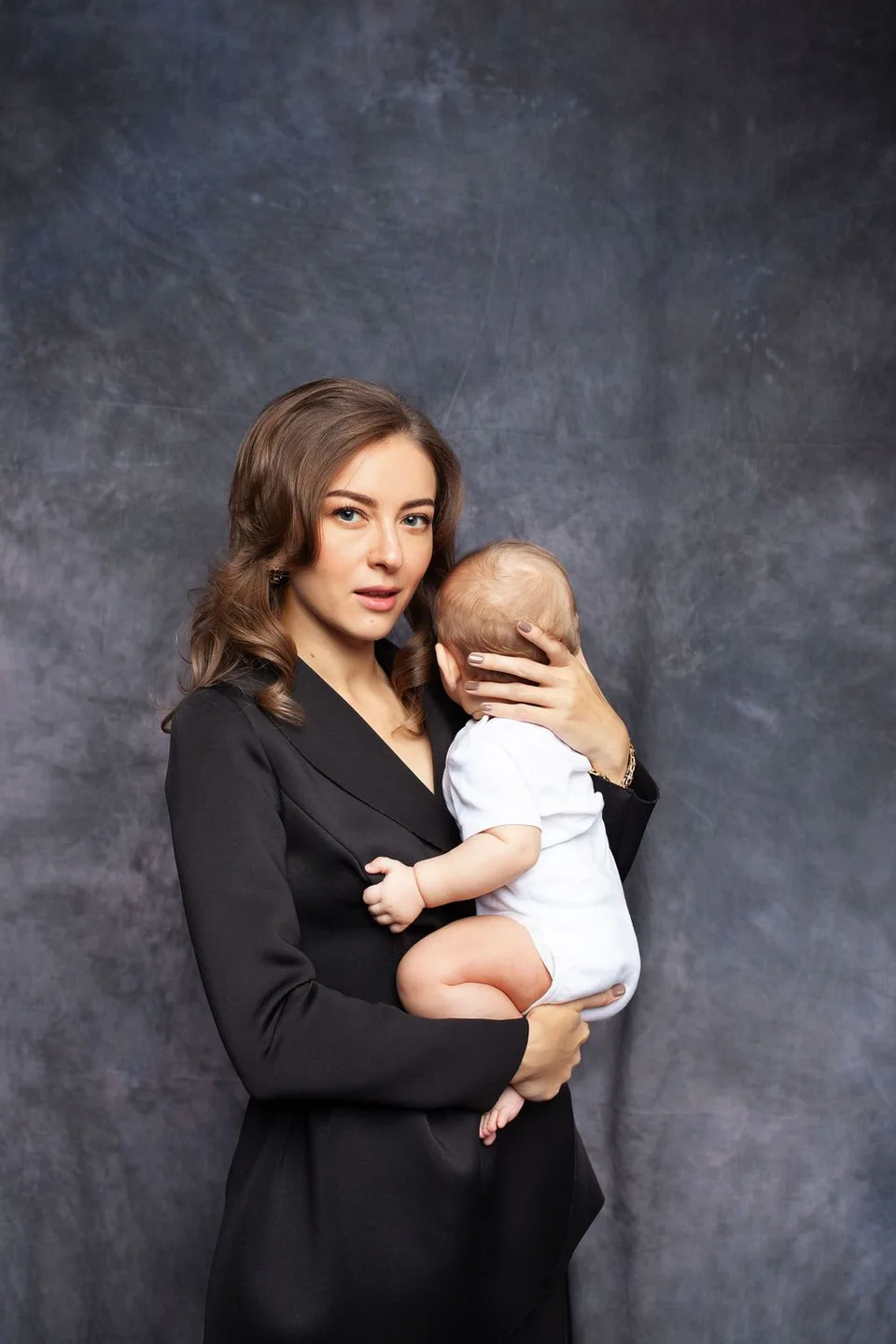 An elegant portrait against a dark grey backdrop featuring a stylish black blazer.