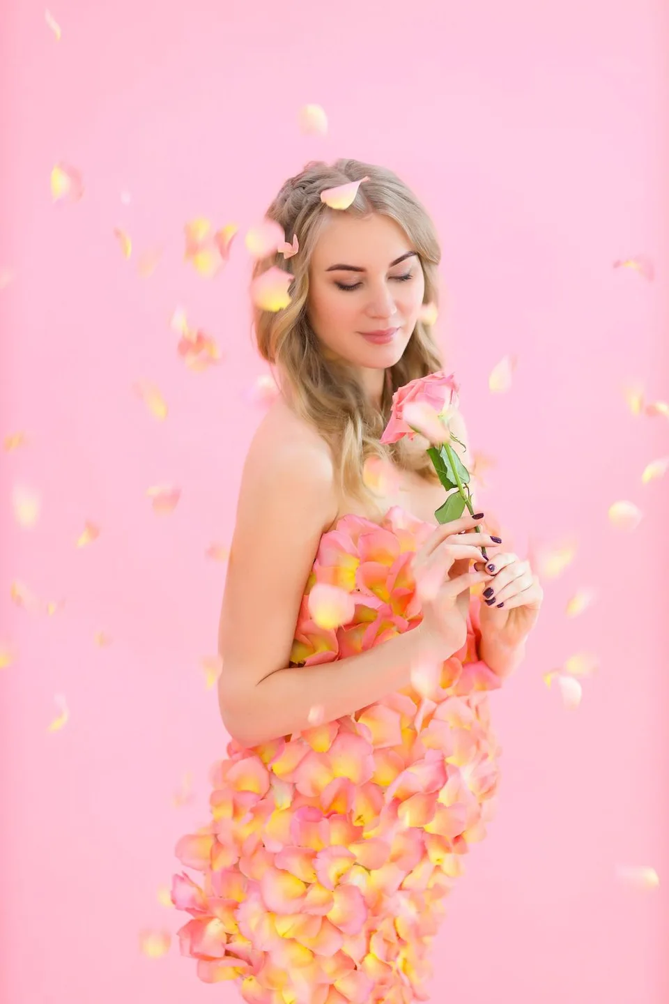 Romantic portrait with rose petals and fairy lights against a pink background.