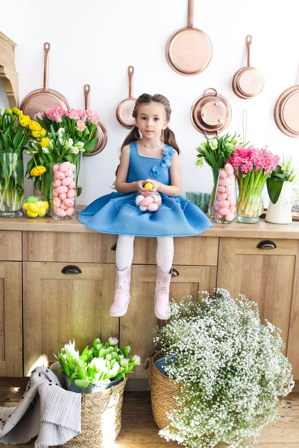 Kitchen decor with copper pans, spring flowers and wooden cabinets.