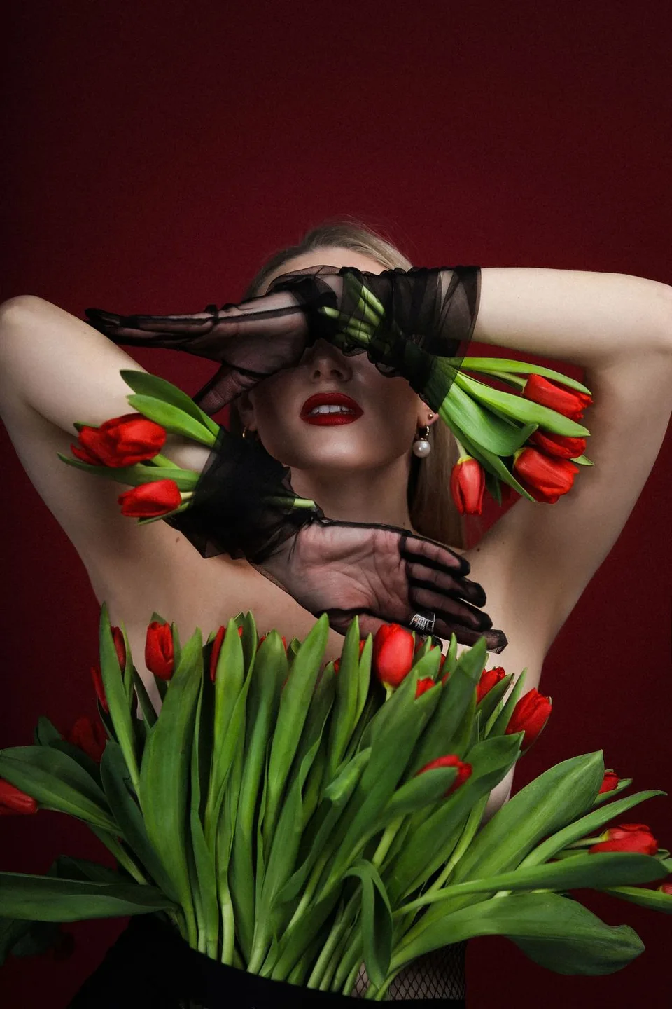 Studio portrait with red tulips against a burgundy backdrop