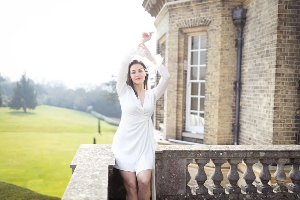 A dreamy bridal portrait in a short white dress on a stone balcony with rolling hills in the background.