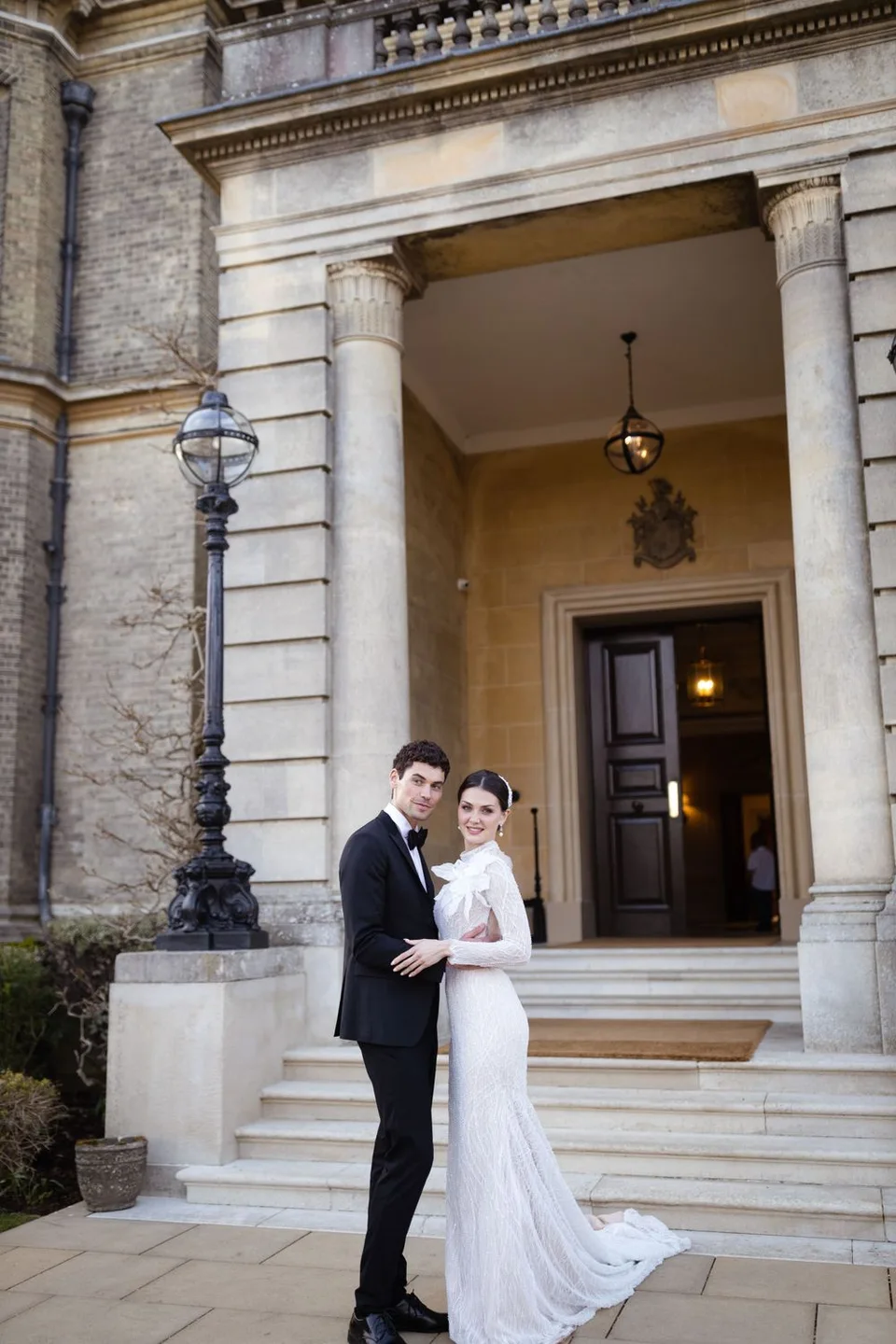 Elegant wedding portrait on grand stone steps of historic building with classical architecture.