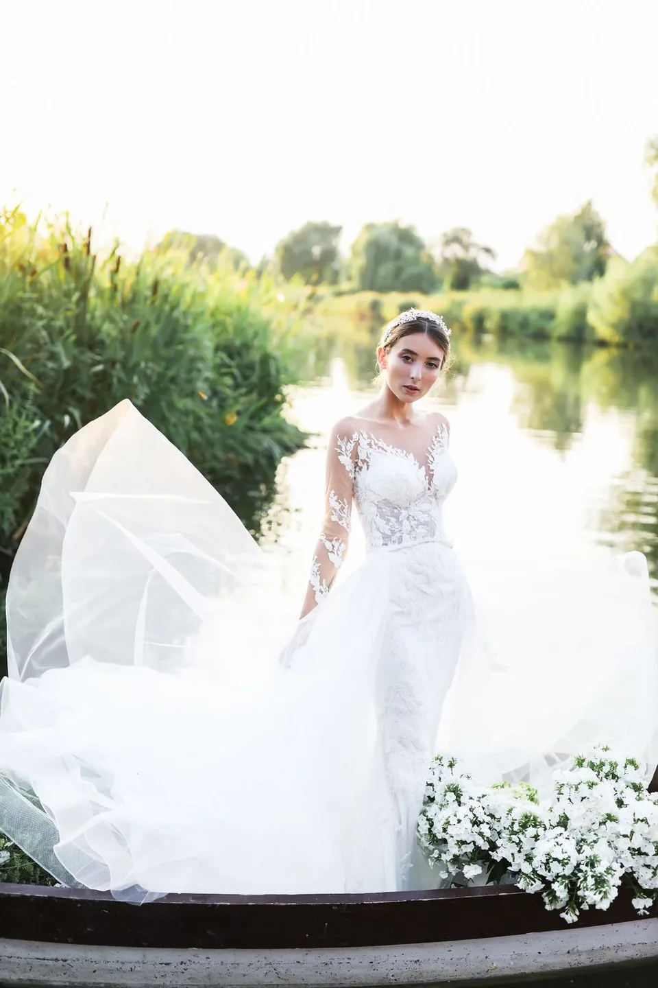 Elegant bridal photoshoot featuring flowing white dress and floral arrangements in rustic boat.