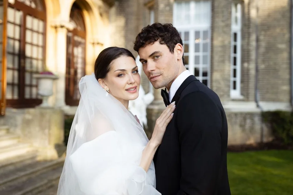 Romantic wedding portrait against historic stone building facade.
