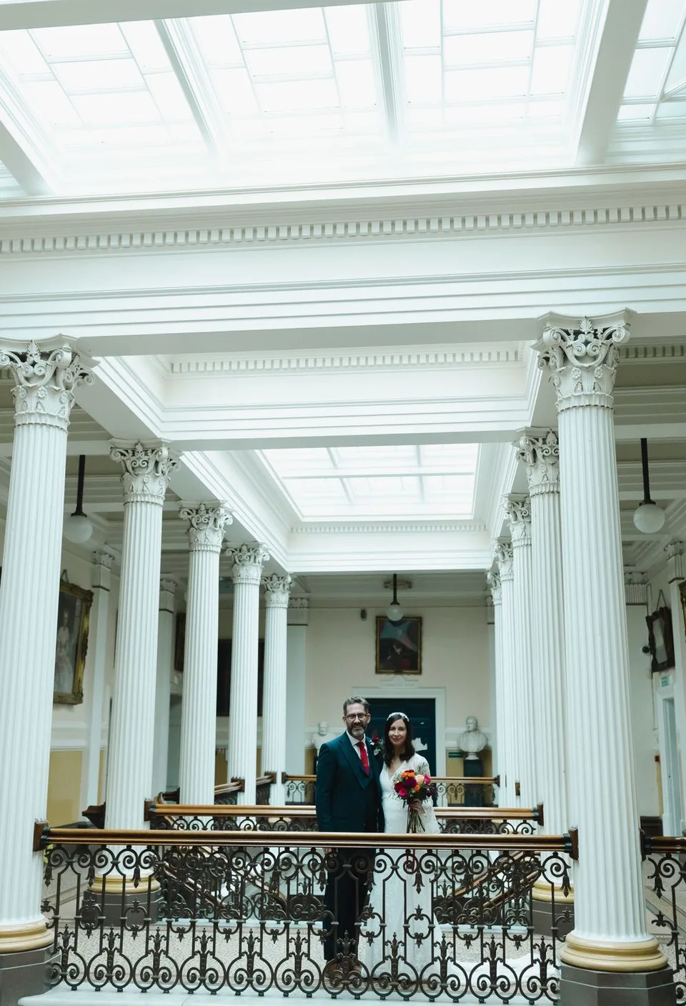 Elegant white columns and skylights create a grand architectural setting for a wedding ceremony.