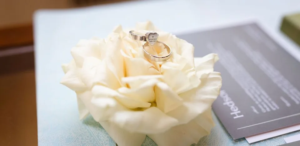Close up of engagement ring delicately placed on white rose petals.