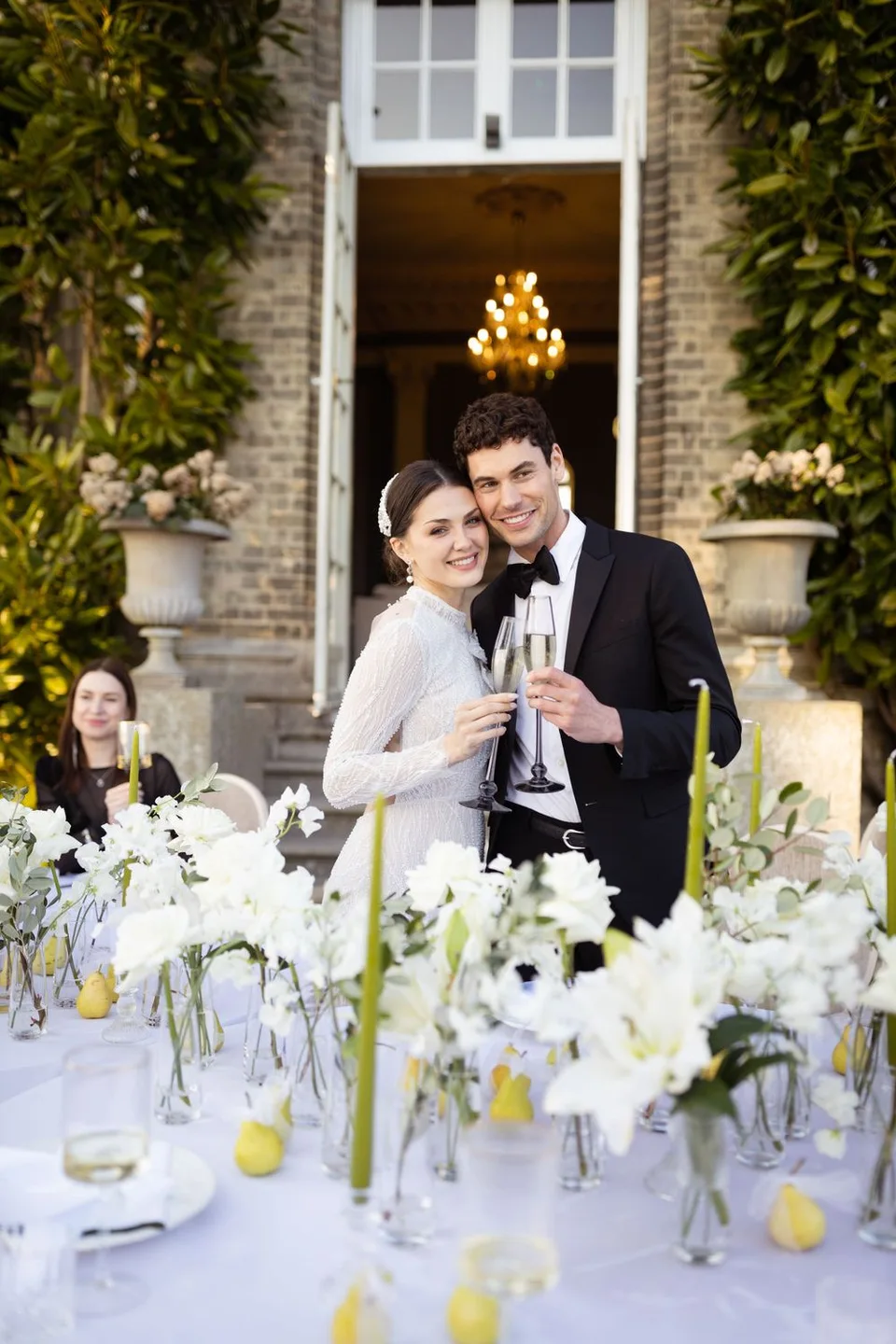 Elegant outdoor wedding reception setup with white floral centerpieces and champagne toast at a historic brick venue.