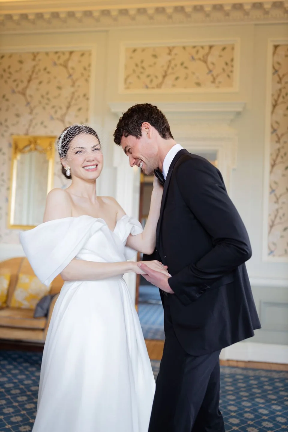 Joyful wedding moment shared in elegant room with decorative crown molding.
