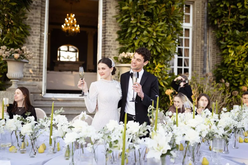 Outdoor wedding reception table with white floral centerpieces and elegant place settings.