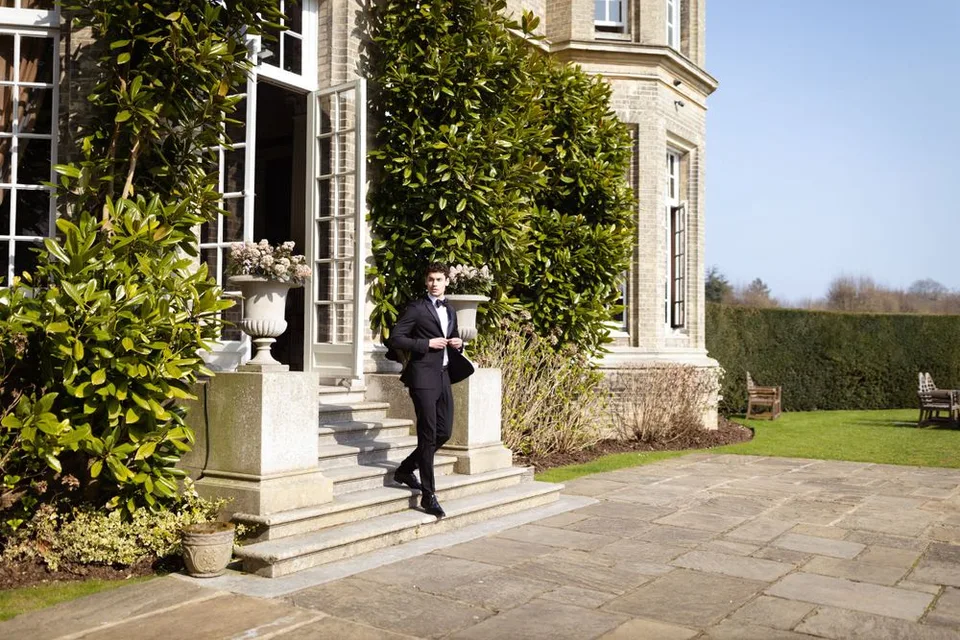 Person in formal wear walking down stone steps of elegant manor house.
