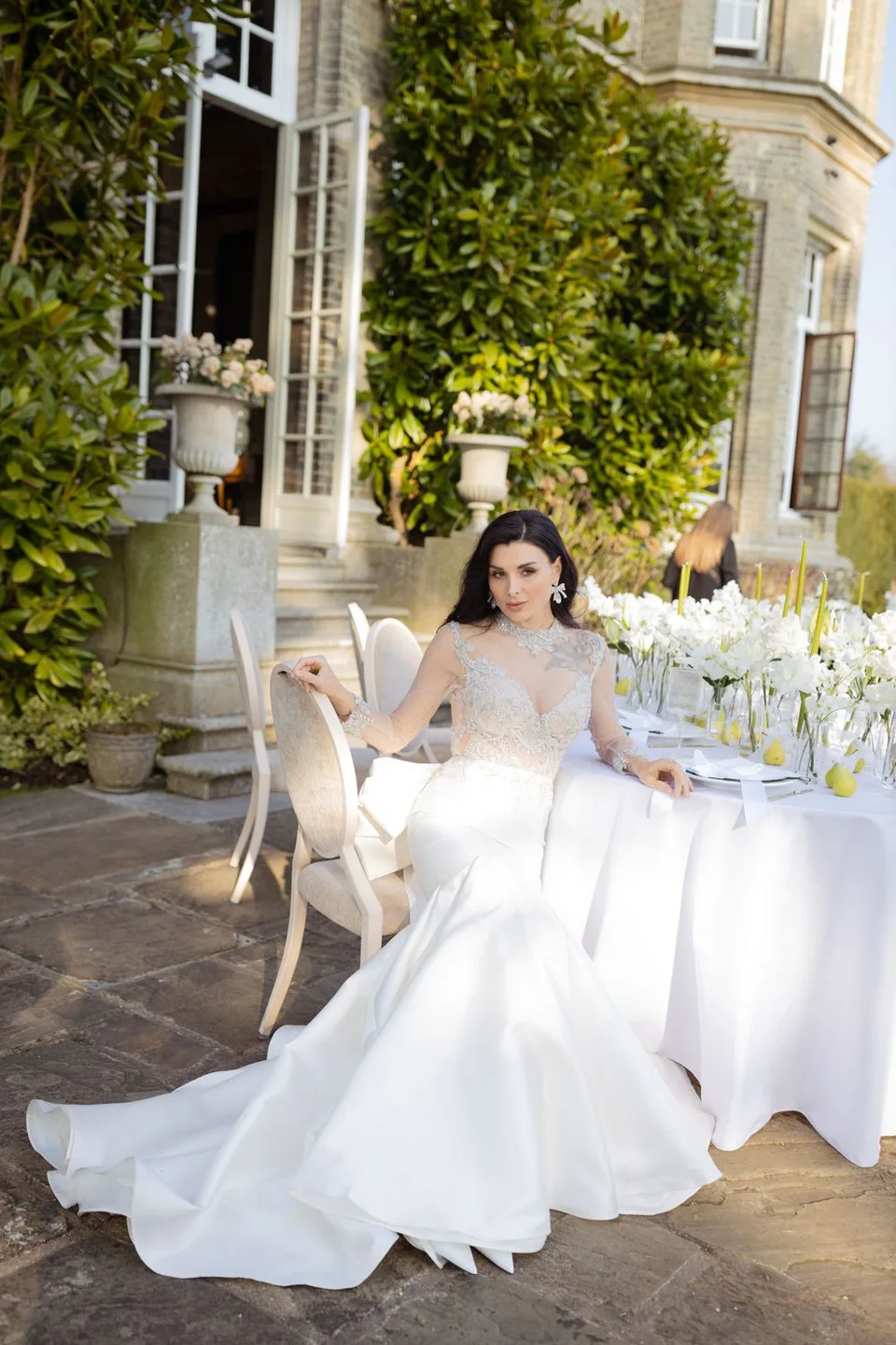 Beautiful bride sitting near the table with stylish arrangements
