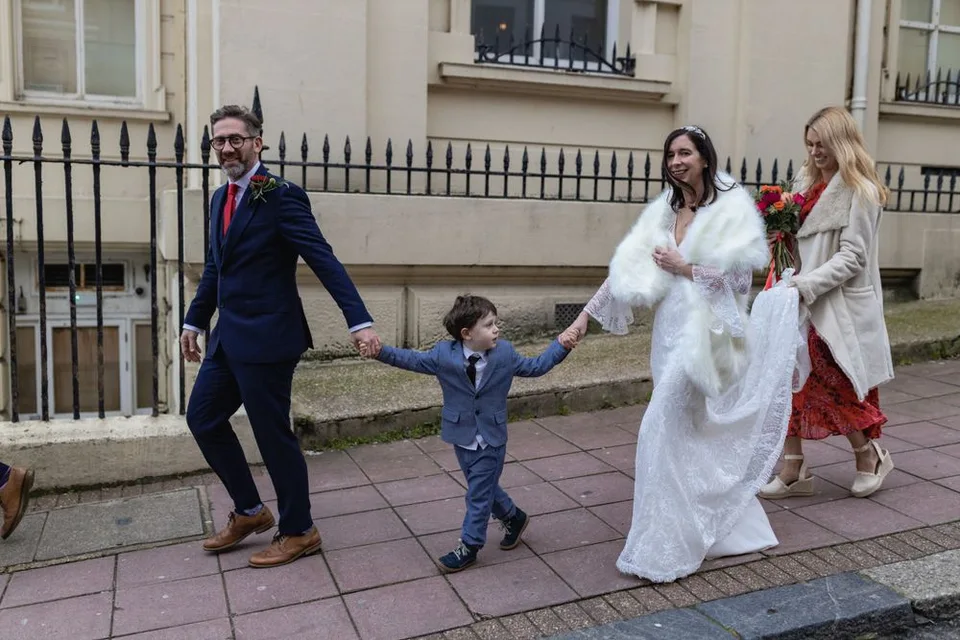 Joyful wedding party dancing and holding hands while walking down a city street.