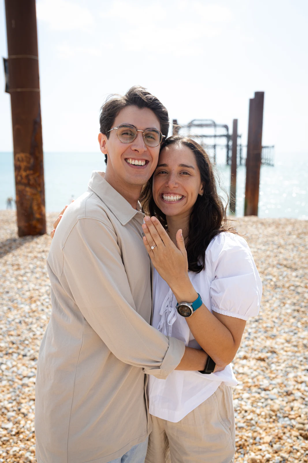 A smiling couple beside the seafront railings in Brighton.