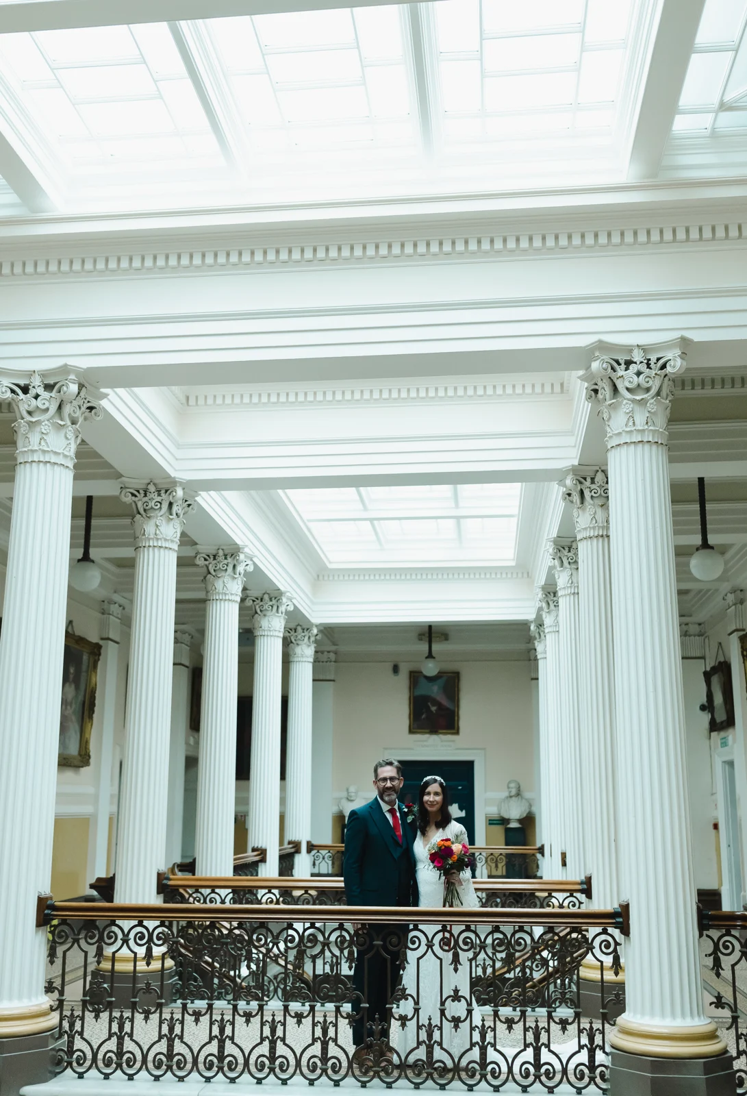 A wedding couple framed by the columns and staircase of Brighton Town Hall.