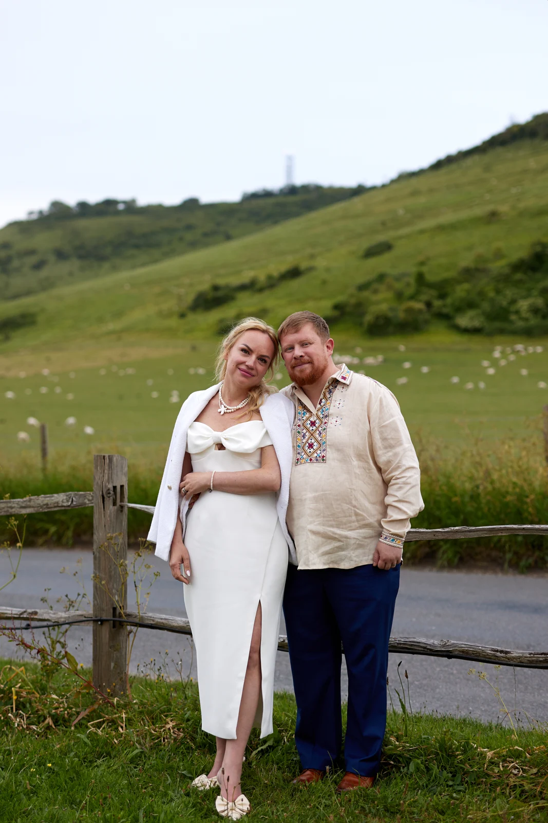 Kate and Rob together beside a fence with the Sussex hills behind them.