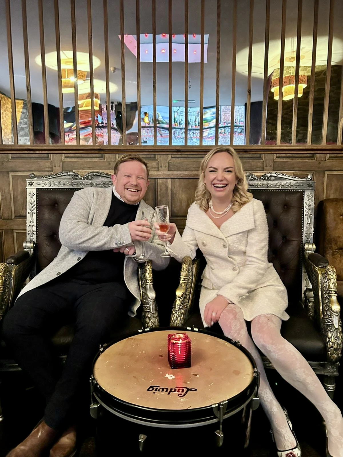 Kate and her husband laughing together and raising their glasses on their wedding day.