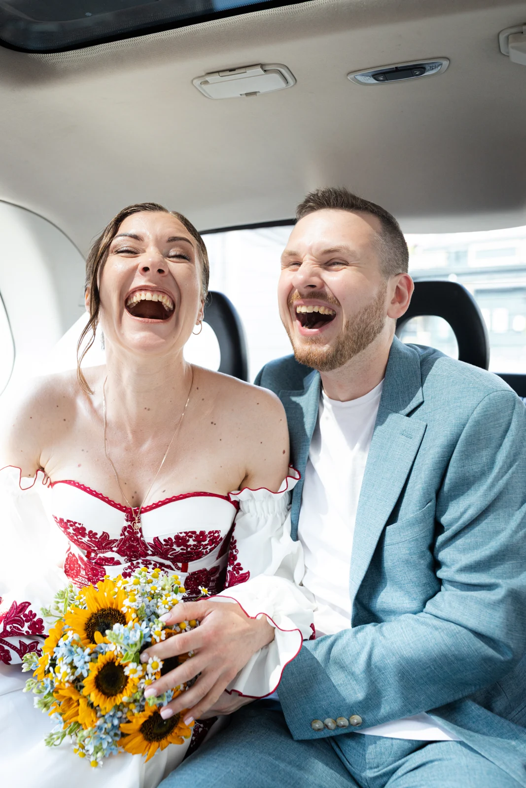 Lena and Arturs laughing together in the back of a taxi.