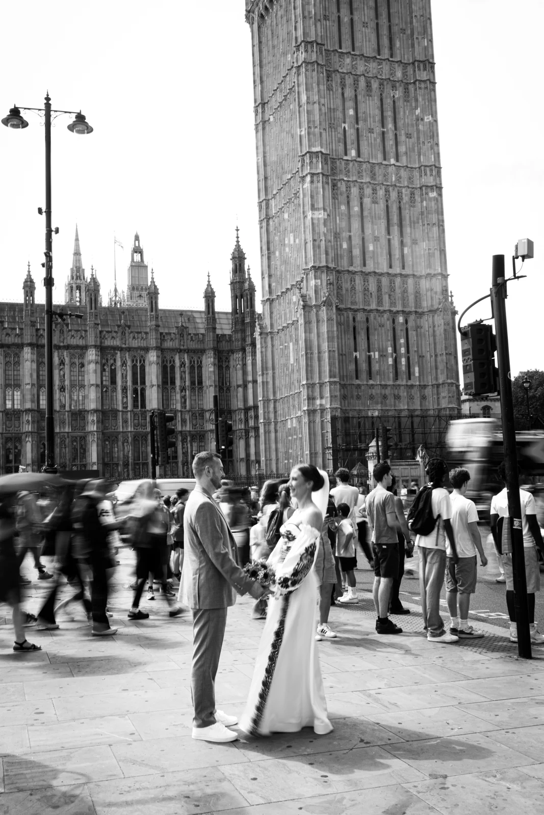 Lena and Arturs holding hands outside Parliament as people pass around them.