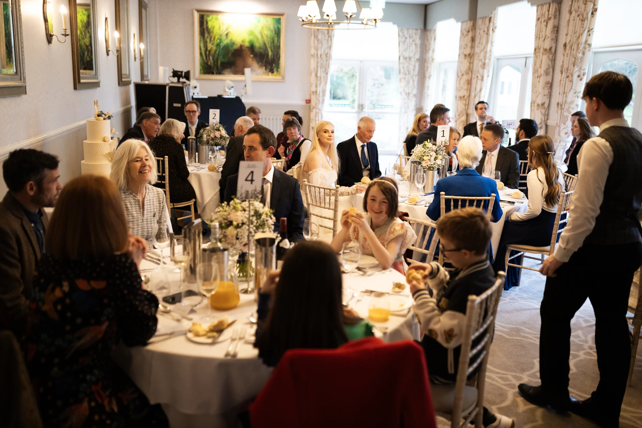 Bride and guests gathered around the tables at an indoor wedding reception.