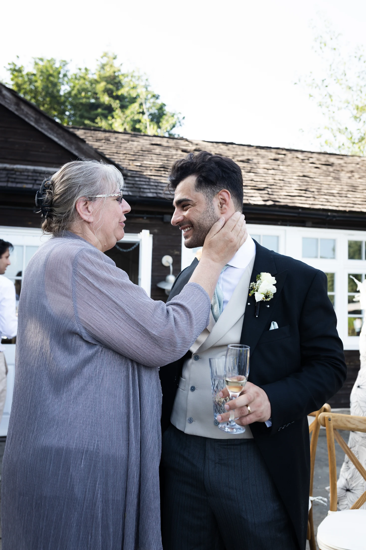 A wedding guest sharing an affectionate moment with the groom.