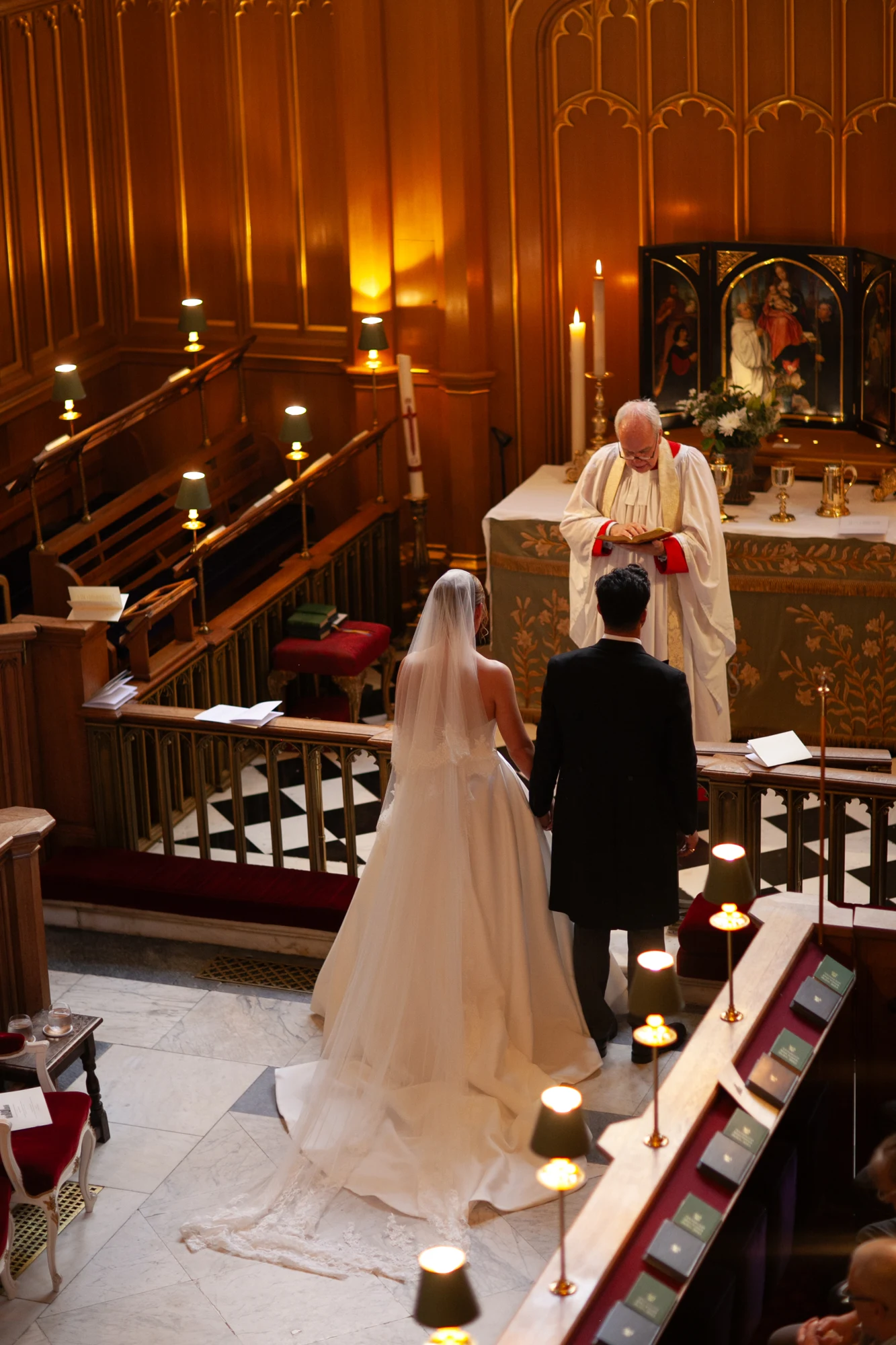 Bride and groom holding hands before the officiant during their chapel ceremony.